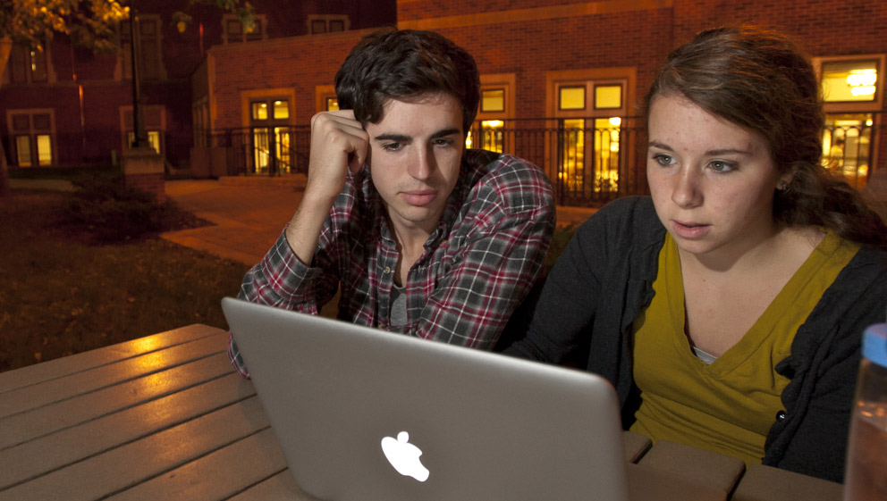 students using the computer together outside in the evening