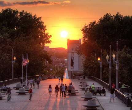 students walking on bridge at sunset