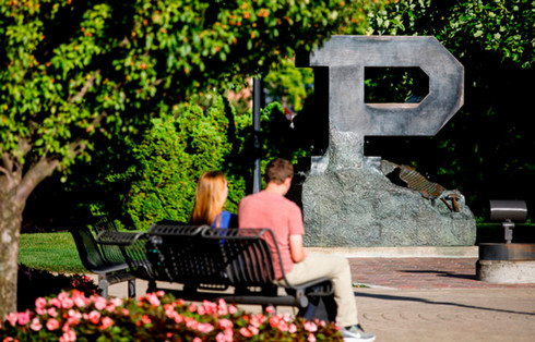 people on bench in front of Purdue P statue in summer